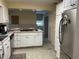 Open kitchen with white cabinets, stainless steel appliances, and an island with a cooktop; needs TLC at 7708 Woodland Dr., Myrtle Beach, SC 29572