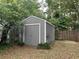 Exterior view of storage shed surrounded by lush greenery and mature trees in backyard at 7708 Woodland Dr., Myrtle Beach, SC 29572