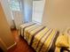 Cozy bedroom with wood flooring, a striped comforter, and natural light from the window at 8 Raymond St., Andrews, SC 29510