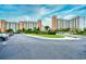 Beautiful exterior view of condo complex featuring a circular drive, lush landscaping, and ample parking at 8121 Amalfi Pl. # 7-805, Myrtle Beach, SC 29572