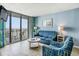 Living room features a cozy blue sofa, patterned armchair, and a sliding glass door to a beach-view balcony at 9400 Shore Dr. # 124, Myrtle Beach, SC 29572