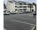 Low angle view of the three-story condo building with rows of parked cars in the parking lot at 1100 Possum Trot Rd. # H-233, North Myrtle Beach, SC 29582