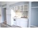 Close-up of kitchenette with new, white appliances, white cabinetry, stainless steel sink, and tiled backsplash at 1100 Possum Trot Rd. # H-233, North Myrtle Beach, SC 29582