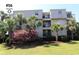 Condo building with lush landscaping, including palm trees and flowering bushes at 1582 South Waccamaw Dr. # 56, Garden City Beach, SC 29576