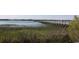 Picturesque waterfront with a long wooden pier surrounded by tall grasses and foliage at 1582 South Waccamaw Dr. # 56, Garden City Beach, SC 29576