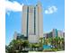 Modern high-rise building features Sand Dunes branding, palm trees, and a bright blue sky at 201 N 74Th Ave. N # 2249/2250, Myrtle Beach, SC 29572