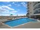 Exterior view of the in-ground pool with tables and chairs overlooking the beach and ocean at 201 S Ocean Blvd. # 1106, North Myrtle Beach, SC 29582