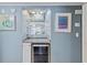This bar area features a wine cooler, granite counter, custom shelving with decorative glassware, and coastal artwork at 202 North Ocean Blvd. # 109, North Myrtle Beach, SC 29582