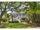 Two-story home boasts dual porches, lush landscaping, and a charming stairway entrance framed by mature trees at 214 Sea Island Dr., Georgetown, SC 29440