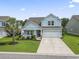 Charming two-story home with a manicured lawn, a two-car garage, and a welcoming front porch at 223 Southgate Ct., Pawleys Island, SC 29585