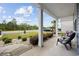 Covered porch with gray chairs, columns, and nicely landscaped front yard with beautiful mature trees at 3573 Bells Lake Circle, Longs, SC 29568