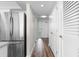 Hallway with luxury vinyl plank flooring and stainless steel refrigerator, leading to a sunlit doorway at 4505 S Ocean Blvd. # 5D, North Myrtle Beach, SC 29582