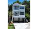 Two-story stilt home featuring balconies, dark shutters, and a concrete driveway and stairs at 52 Fish Shack Alley, Murrells Inlet, SC 29576