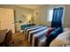 Relaxing bedroom with a queen bed, striped bedding, a blue dresser, and a bright window with a blue curtain at 5409 N Ocean Blvd. # 111, North Myrtle Beach, SC 29582