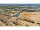 Aerial scene of a metal building and pond, surrounded by open fields and interspersed with woods at 589 Loop Circle, Longs, SC 29568