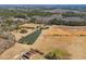Overhead view of a home, metal building, and pond amidst open land with trees and fields at 589 Loop Circle, Longs, SC 29568