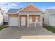 Charming peach-colored home featuring a metal roof, a quaint front porch, and an attached garage at 603 Wave Rider Ln. # 603, North Myrtle Beach, SC 29582