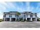 Three-story condo building with covered parking, lush landscaping, and a picturesque palm tree at 701 Norris Dr., Pawleys Island, SC 29585