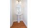 Small powder room features a pedestal sink, oval mirror, and wood flooring at 112 Molinia Dr., Murrells Inlet, SC 29576