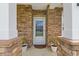 Welcoming front porch with stone columns, decorative plants, and a glass-paneled white door at 131 Crabapple Dr., Longs, SC 29568