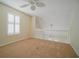 Bright bedroom with neutral carpet and plantation shutters, next to a staircase landing with white railings at 153 Wimbledon Way # 153, Murrells Inlet, SC 29576