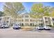 Three-story condo building featuring parking and mature landscaping and trees on a sunny day at 1550 Spinnaker Dr. # 3123, North Myrtle Beach, SC 29582