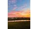 Serene pond reflecting a vibrant sunset sky, with the silhouettes of houses creating a peaceful neighborhood scene at 1709 Perthshire Loop, Myrtle Beach, SC 29579