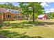Expansive backyard with mature trees, a brick house, and a red barn, offering a serene outdoor setting at 1961 Bright Rd., Little River, SC 29566