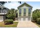 Inviting two-story home with a two-car garage and green exterior, complemented by lush landscaping at 281 Lumbee Circle, Pawleys Island, SC 29585