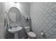 Stylish powder room with patterned wallpaper, a round mirror, and elegant towel holders at 281 Lumbee Circle, Pawleys Island, SC 29585