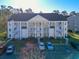 Three-story building with yellow siding, white trim, and multiple staircases, surrounded by parking and trees at 5822 Longwood Dr. # 104, Murrells Inlet, SC 29576