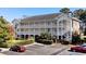 Beautiful two-story condo building with white siding, balconies, manicured landscaping, and ample parking at 703 Riverwalk Dr. # 303, Myrtle Beach, SC 29579
