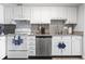 Bright kitchen with stainless steel appliances and white cabinets, complemented by a tile backsplash and wooden floors at 920 N Waccamaw Dr. # 1302, Garden City Beach, SC 29576