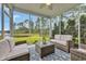 Inviting screened porch with wicker furniture and a beautiful view of the lake and lush green landscape at 933 Wild Leaf Loop, Conway, SC 29526