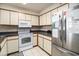 Kitchen featuring white appliances, cream cabinets, and dark countertops with white tile floors at 1425 S Ocean Blvd. # 2A, North Myrtle Beach, SC 29582