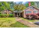 Charming brick home featuring a brick walkway, mature trees, lush landscaping, and a welcoming American flag at 196 John Waites Ct., Georgetown, SC 29440