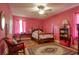 Pink bedroom features a four-poster bed with floral bedding, ceiling fan, desk, and area rug at 2004 Seitter St., Georgetown, SC 29440