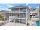 Three-story home featuring double balconies, gray siding, a brick driveway, and a well-manicured landscaped perimeter at 204 33Rd Ave. N, North Myrtle Beach, SC 29582