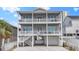 Three-story gray beach house featuring double balconies, white railings, and a charming paver driveway at 204 33Rd Ave. N, North Myrtle Beach, SC 29582