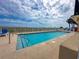 Exterior shot of a pool with an ocean view under a cloudy sky at 2101 S Ocean Blvd. # A-4, North Myrtle Beach, SC 29582