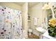 Bright bathroom featuring a tub with floral shower curtain, pedestal sink, and neutral tones at 2180 Waterview Dr. # 635, North Myrtle Beach, SC 29582