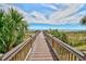 Wooden walkway leads to the beach surrounded by lush green tropical vegetation at 2310 N Ocean Blvd. # 1107, Myrtle Beach, SC 29577