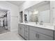 Bathroom with double sinks, gray cabinets, chrome fixtures, large mirror, and access to a walk-in closet at 4206 Falls Oaks St., Myrtle Beach, SC 29579