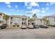 Condo building featuring stone facade, balconies, palm trees and ample parking on a sunny day at 4767 Wild Iris Dr. # 203, Myrtle Beach, SC 29579