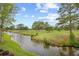 Scenic golf course view featuring a meandering stream and lush greenery under a blue sky with fluffy clouds at 4767 Wild Iris Dr. # 203, Myrtle Beach, SC 29579