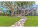 Landscaped backyard featuring a covered patio with staircase, lush lawn, and brick walkway at 510 Rum Gully Rd., Murrells Inlet, SC 29576