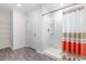 Bright bathroom featuring a walk-in shower with neutral-toned tile and glass, plus shelving and a door in the background at 555 Strawberry Field Way, Galivants Ferry, SC 29544