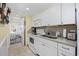 Fully-equipped kitchen with white cabinets and appliances, and adjoining room with bed at 601 Retreat Beach Circle # 213, Pawleys Island, SC 29585