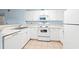 Well-lit kitchen featuring white cabinetry, stainless sink, white appliances, and tiled flooring at 6016 Dick Pond Rd. # 109, Myrtle Beach, SC 29588