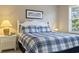 Comfortable bedroom features a bed with a blue and white plaid comforter, white headboard and matching white nightstand at 6253 Catalina Dr. # 534, North Myrtle Beach, SC 29582